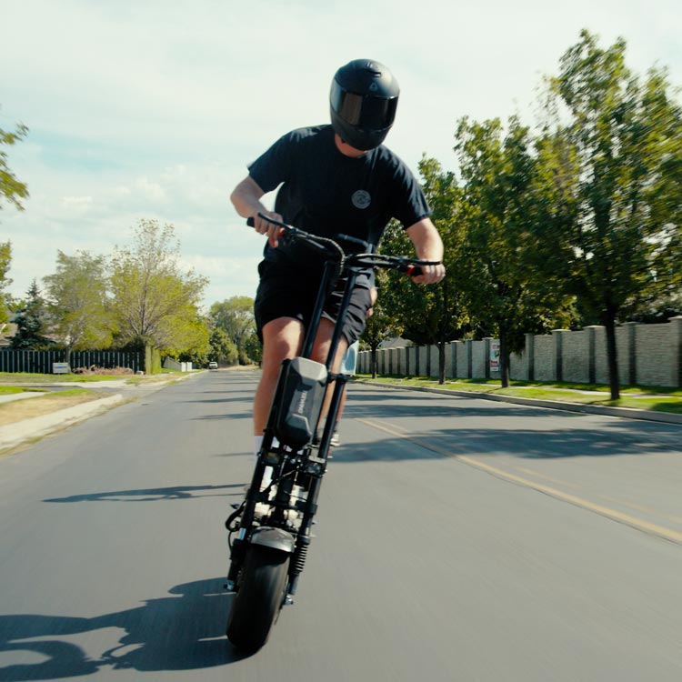 Riding TEEWING Z4 PRO electric scooter on a road with trees